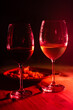 Silhouette of two glass glasses with wine on a wooden table. Predominant red light.