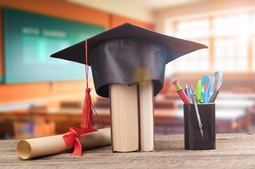 Wall Mural - A Graduation cap on stack of books on the table.