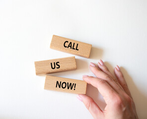 Sticker - Call us now symbol. Wooden blocks with words Call us now. Beautiful white background. Businessman hand. Business and Call us now concept. Copy space.