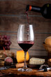 glass of red wine with cheese board country bread wooden board still life fresh grapes and bottle