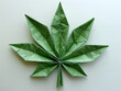 A green origami cannabis leaf on a white background, showcasing intricate paper folding art.