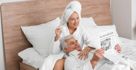 Wall Mural - Mature couple reading newspaper in bedroom