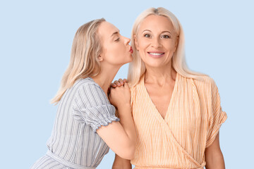 Canvas Print - Happy young beautiful woman kissing her mother on blue background