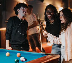 Wall Mural - A group of friends enjoys a happy night out together, playing billiards and having fun in a cozy bar.