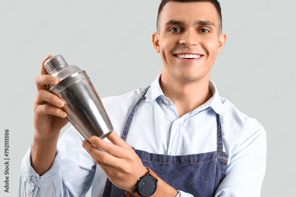 Young male bartender with shaker on white background