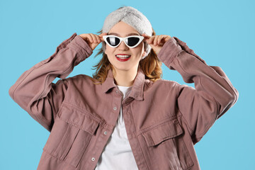 Sticker - Smiling young woman in headband with sunglasses on blue background