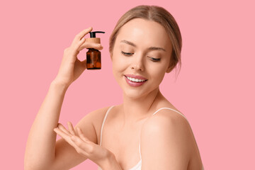 Wall Mural - Beautiful young woman with bottle of cosmetic product on pink background