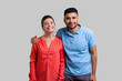 Portrait of smiling family couple standing together hugging looking at camera expressing positive emotions, being in good mood. Indoor studio shot isolated on gray background.