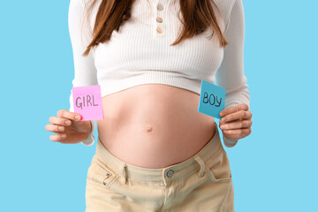 Canvas Print - Beautiful pregnant woman holding papers with gender on blue background, closeup