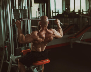 Wall Mural - Caucasian man doing lat pull-downs on a machine. 