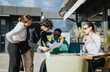© qunica.com - Multiethnic business associates discussing sales, marketing, and strategies for growth during an outdoor meeting at a coffee bar.
