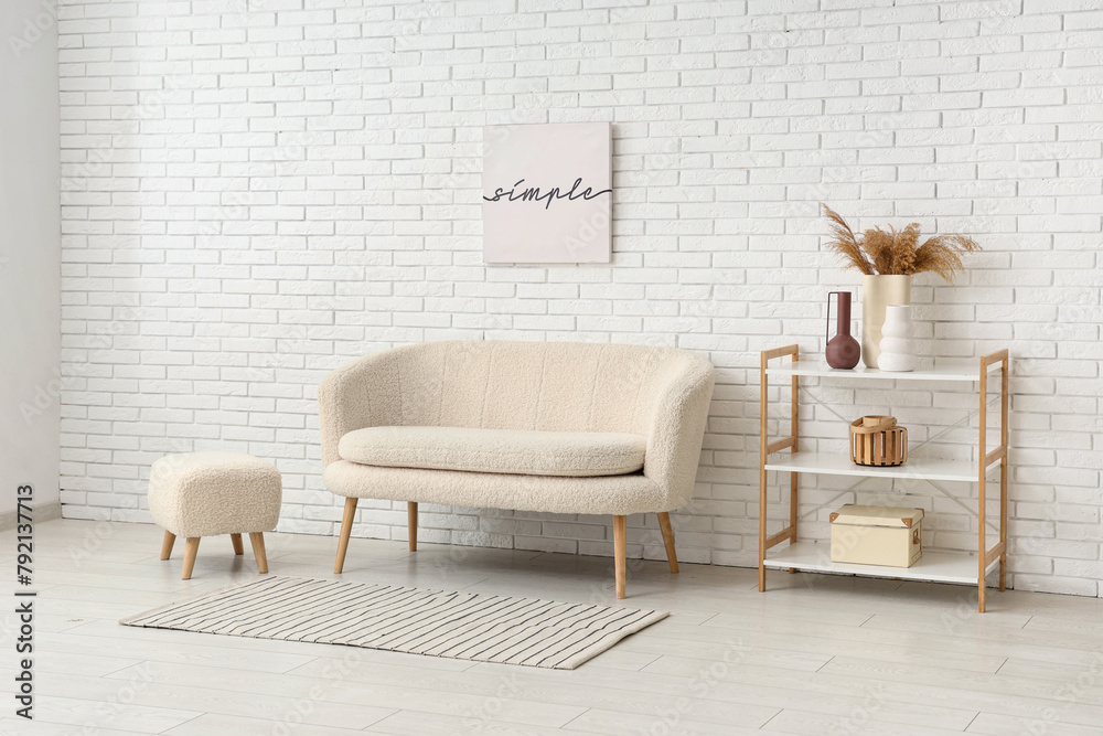 Comfortable sofa, pouf and shelving unit in interior of light living room