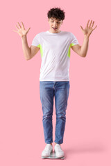 Poster - Handsome young happy sporty man with scales on pink background. Weight loss concept