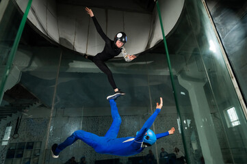 Wall Mural - A man and a woman enjoy flying together in a wind tunnel. Free fall simulator