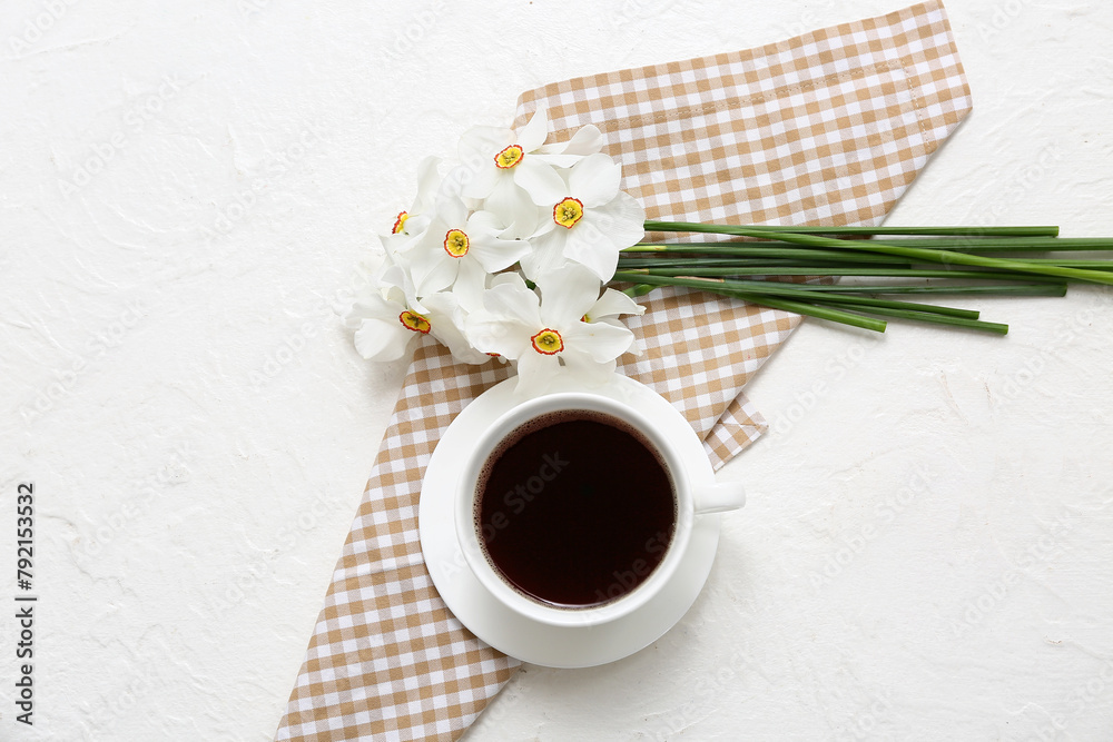 Daffodil flowers on cloth with cup of coffee on white background. Top view