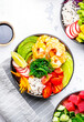 Poke bowls with vegetables and seafood in assortment, white table background, top view