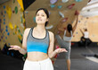 Young sports central asian woman posing against background of wall at climbing wall