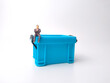 Miniature people are sitting on a blue miniature storage basket box