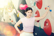 Young central asian woman in sportswear posing near training wall at climbing wall