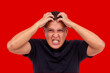 A middle-aged man looking frustrated, furiously scratching his head and seething with anger. About to snap from rage. Accentuated with red background.