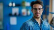 © Suryani - Confident Young Male Professional with Glasses in Blue Denim Shirt at Modern Workplace, Concept of Business and Startup Innovation