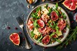 Autumn salad with figs prosciutto cheese rucola nuts and pomegranate on black table Low carb keto friendly