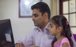 Indian father assisting his teenage daughter with remote learning at home engaging in virtual classes and studying together on a computer