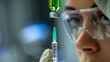 Closeup of a lab technician holding a syringe filled with a bright green liquid a look of indifference on their face. .