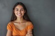 © LimeSky - Smiling young Latin woman with crossed arms standing against grey wall