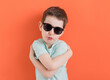 Caucasian boy in sunglasses orange background