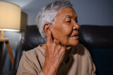 Fototapeta Lawenda - senior woman with symptom of hearing loss while sitting on sofa in the living room at night