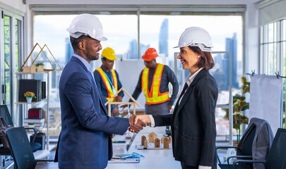 African American manager is handshaking with Caucasian female partner for global industrial development project with modern business district skyscraper building background