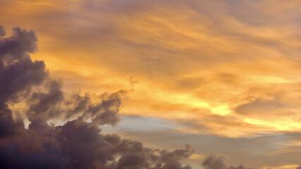 View of the clouds during sunset. Cerocumulus and cumulus clouds in the sky are colored yellow by the rays of the setting sun.