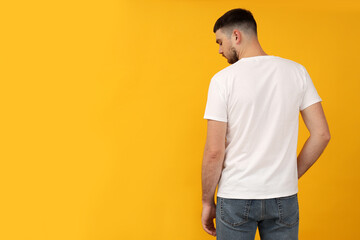 Wall Mural - A young guy in a white t-shirt on a yellow background