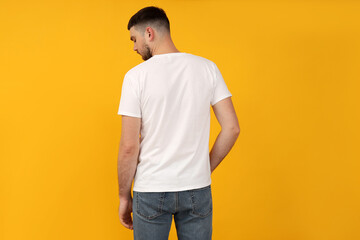 A young guy in a white t-shirt on a yellow background