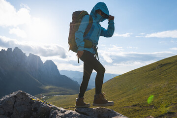 Wall Mural - Successful woman backpacker hiking on sunset alpine mountain top