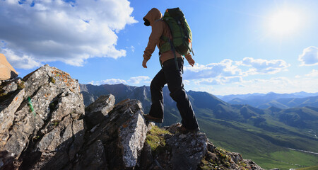 Wall Mural - Successful woman backpacker hiking on sunset alpine mountain top