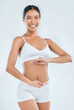 © peopleimages.com - Body, digestion and hands on stomach for woman in studio, nutrition and gut health on white background. Wellness, healthy goals and portrait of female model, diet and balance fitness lifestyle