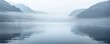 Misty morning over a serene lake surrounded by forested mountains