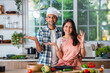 Indian asian couple promoting, showing or holding kitchen utensils in kitchen