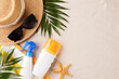 Beach getaway essentials, flat lay of hat, sunglasses, and sunblock on sandy background with copy space