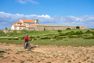 Wall Mural - woman with electric mountain bike at Santuário de Nossa Senhora do Cabo Espichel, a famous pilgrims church at Cabo Espichel near Sesimbra, Portugal
