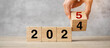 © Jo Panuwat D - hand flipping block 2024 to 2025  text on table. Resolution, strategy, plan, goal, motivation, reboot, business and New Year holiday concepts