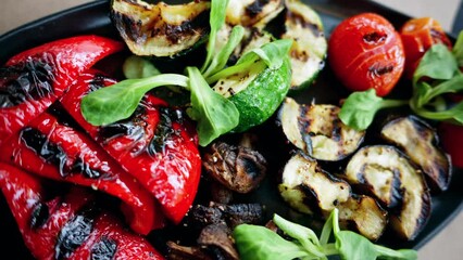 Wall Mural - A black plate of grilled peppers, cherry tomatoes, zucchini, eggplant and mushrooms