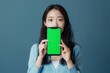 © Markus Schröder - Device screen asian woman in her 30s holding an smartphone with a fully green screen