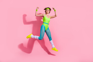 Wall Mural - Photo of positive trainer lady jumping demonstrate strong muscles hands after exercise isolated paste color background