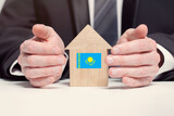 Fototapeta  - Businessman hand holding wooden home model with Kazakhstan flag. insurance and property concepts