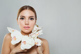 Fototapeta  - Glorious model woman with natural make-up, healthy skin and white flower. Female beauty, cosmetology and skincare concept