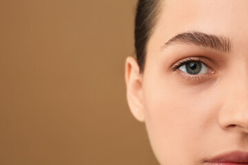 Poster - Young woman with perfect eyebrows on brown background, closeup. Space for text