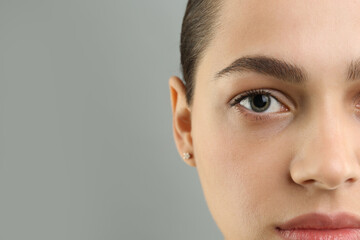 Poster - Young woman with perfect eyebrows on grey background, closeup. Space for text